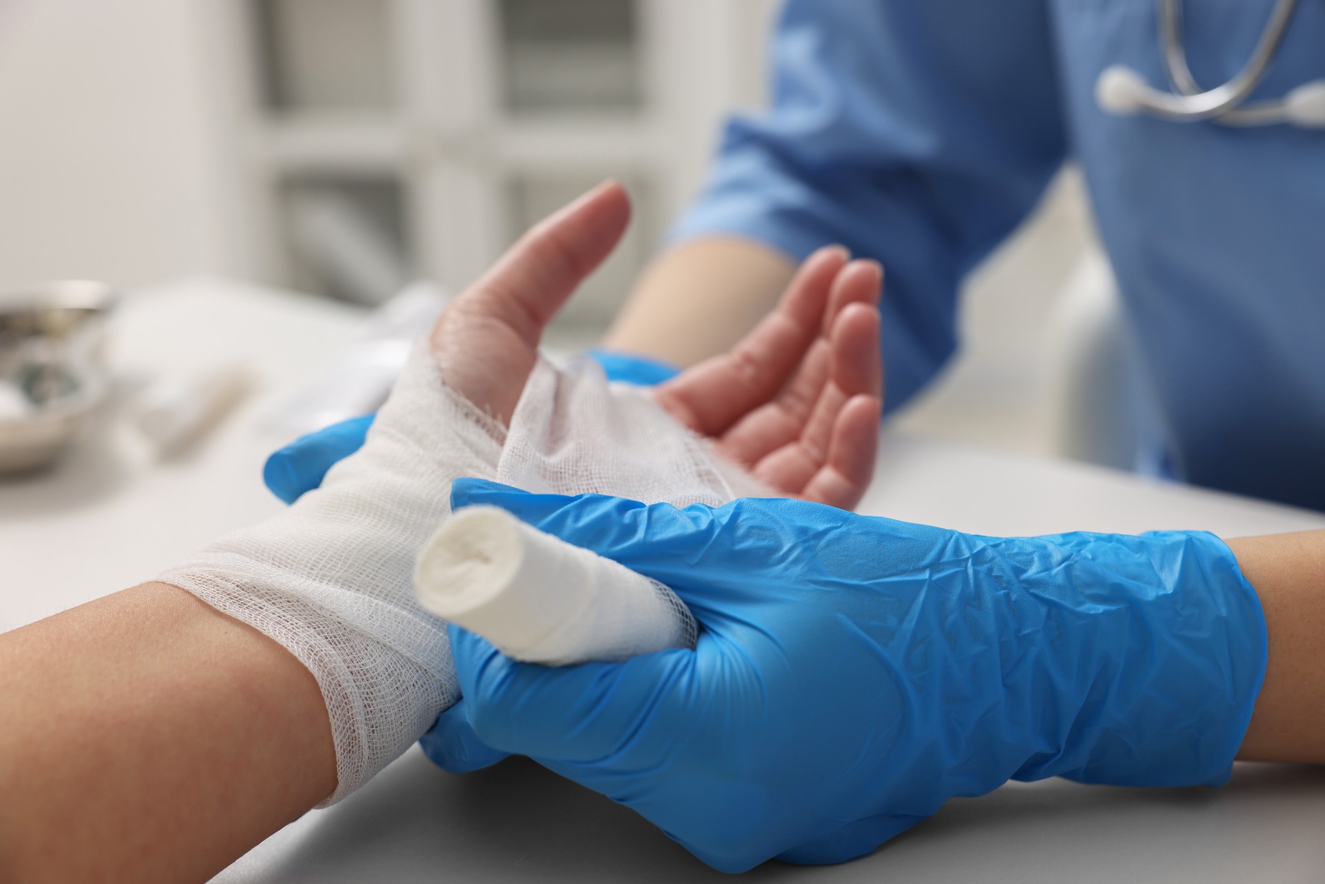 Doctor bandaging patient's burned hand in hospital, closeup