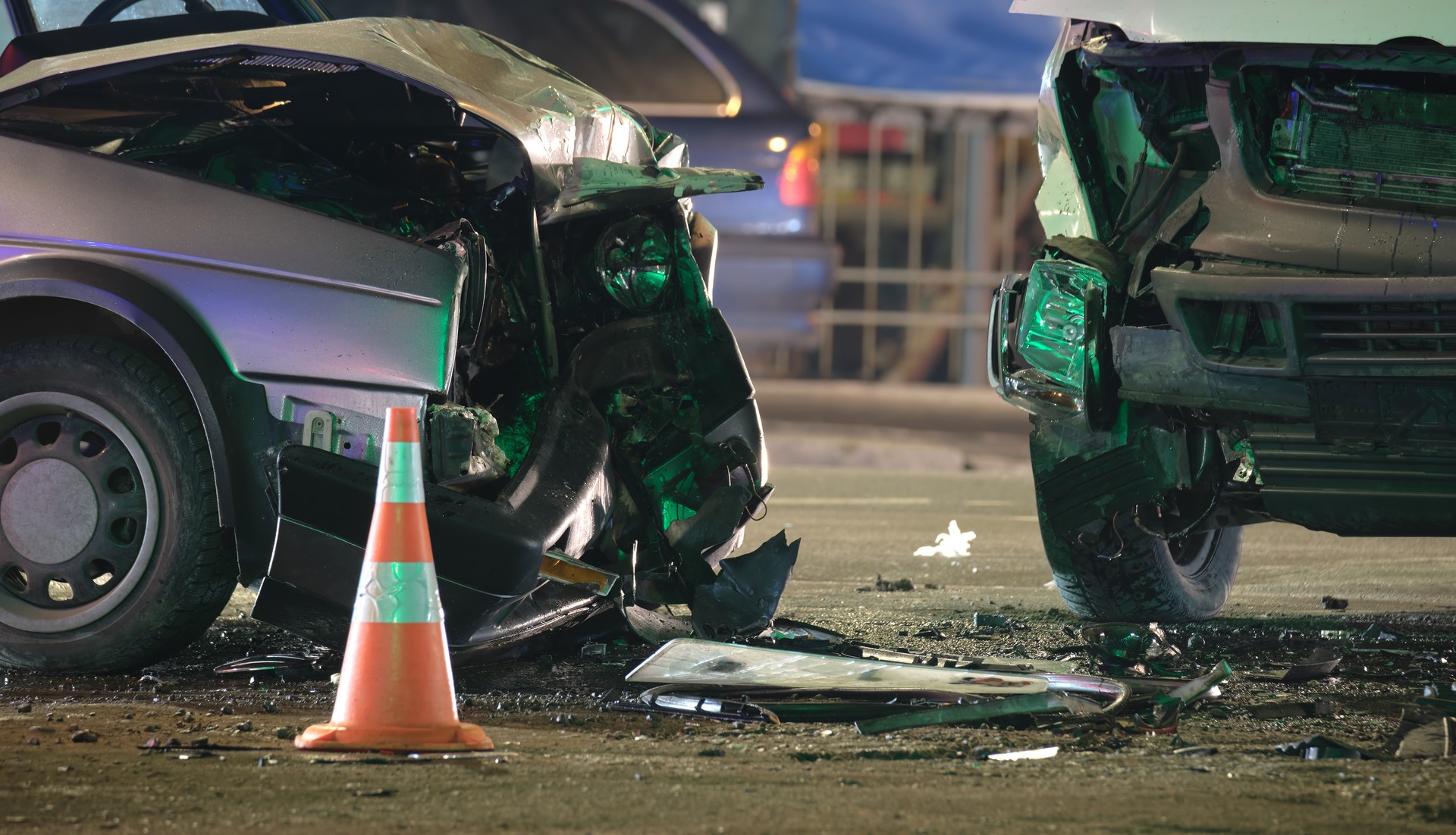 Damaged in heavy car accident vehicles after collision on city street crash site at night. Road safety and insurance concept