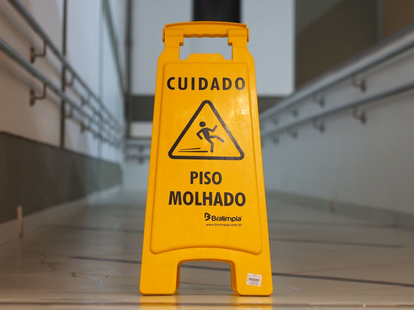 A yellow caution wet floor sign standing in an indoor corridor — the classic warning at the centre of public-place injury cases
